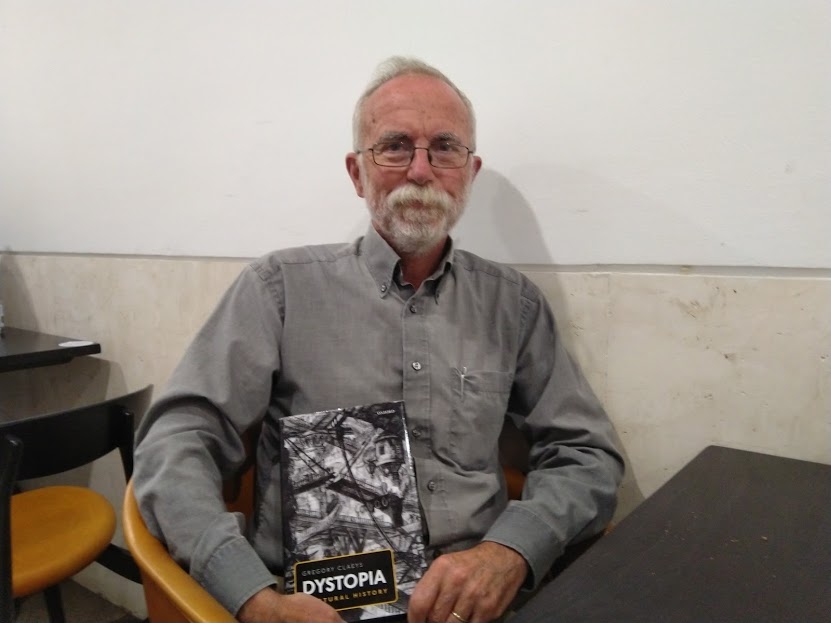 Professor Gregory Claeys sitting with his book Dystopia: A Natural History